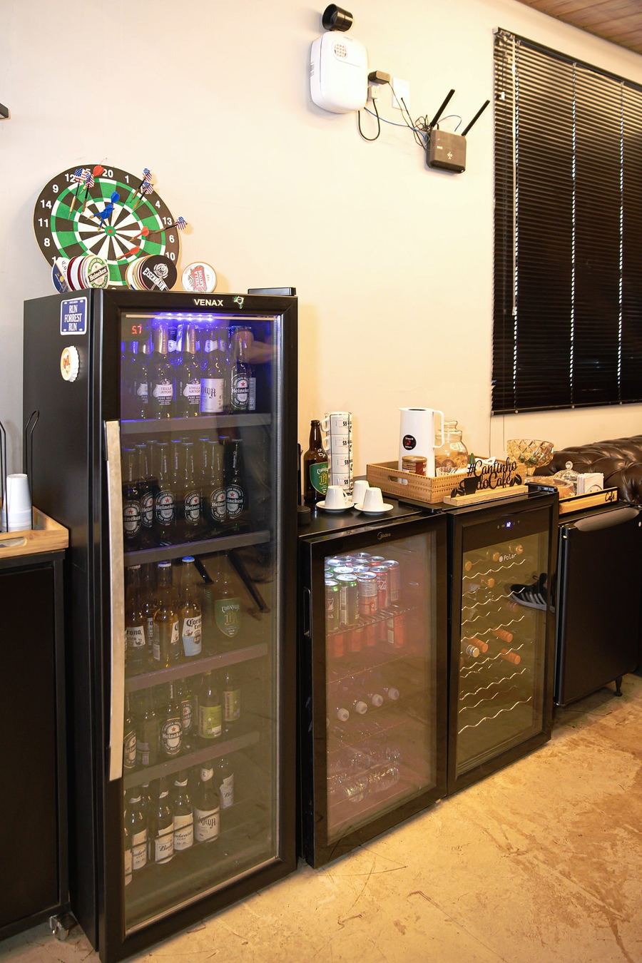 Cantinho do café com cafeteira, xícaras e geladeiras de bebidas